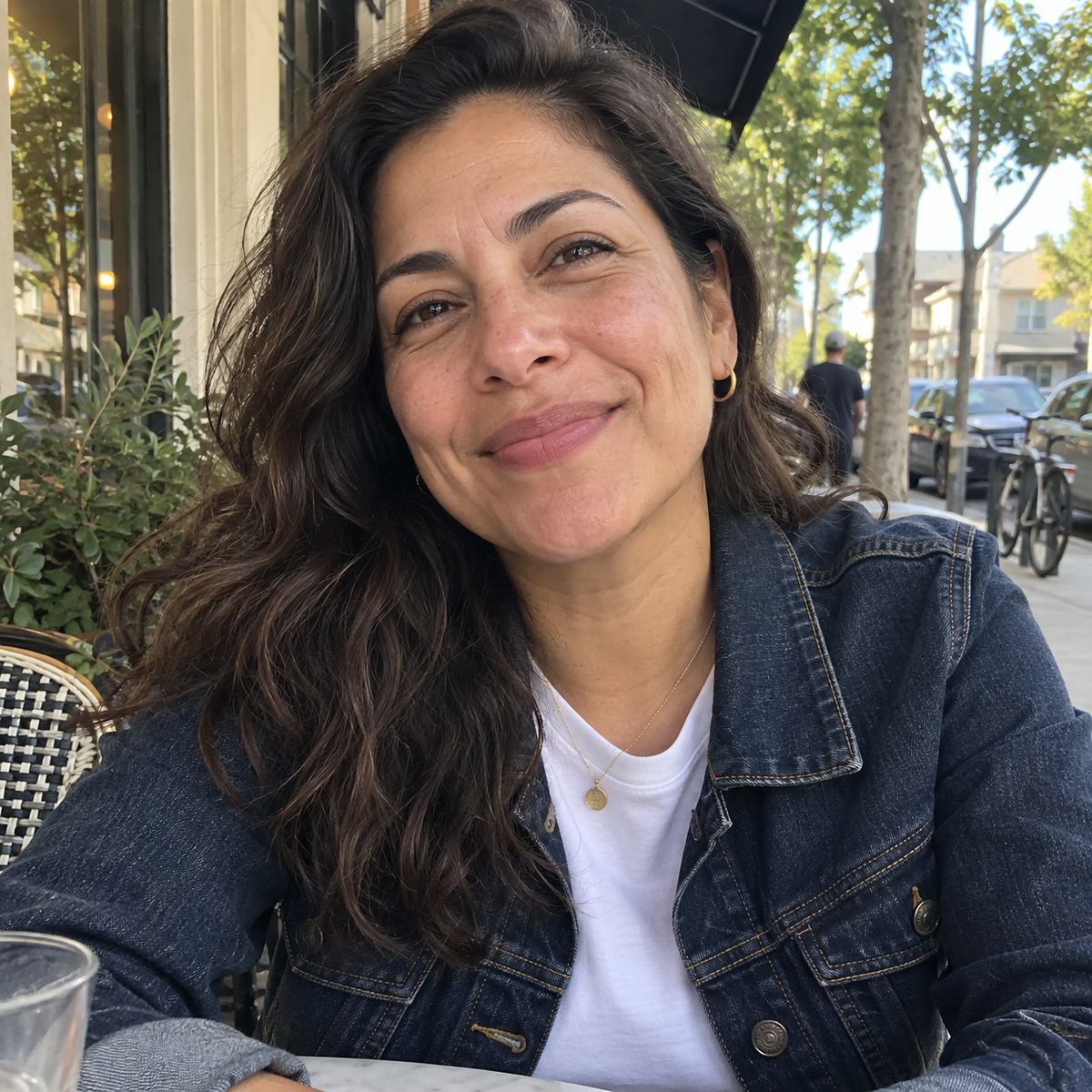 Woman smiling during a casual moment at a sidewalk cafe